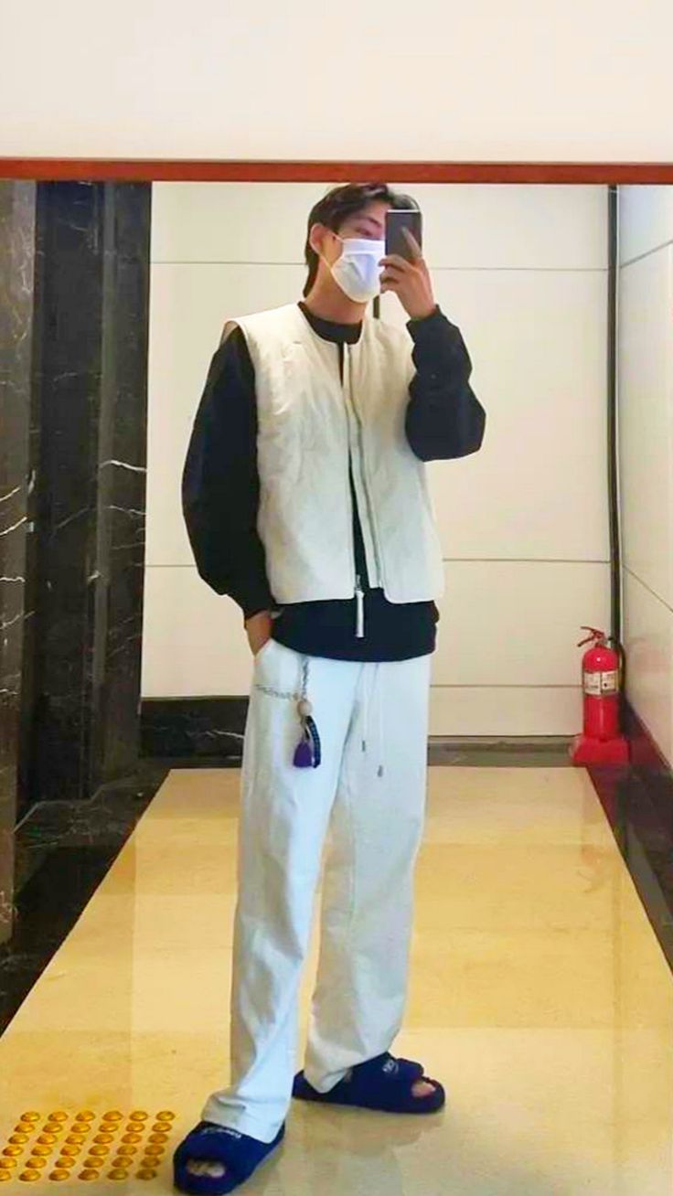 a man standing in front of a mirror taking a selfie with his cell phone