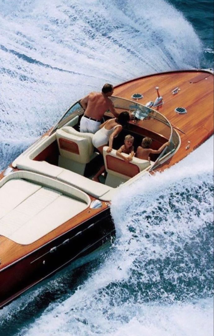 two people are riding in a motorboat on the water while another person is standing behind them