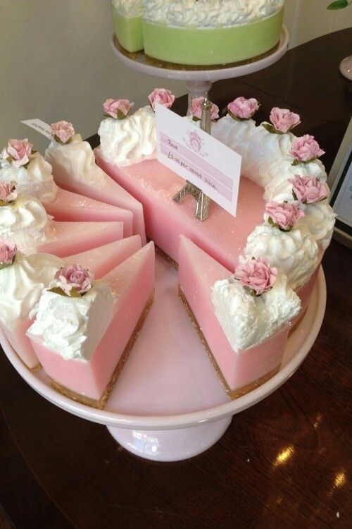 there is a pink cake with white frosting on it and flowers around the edges