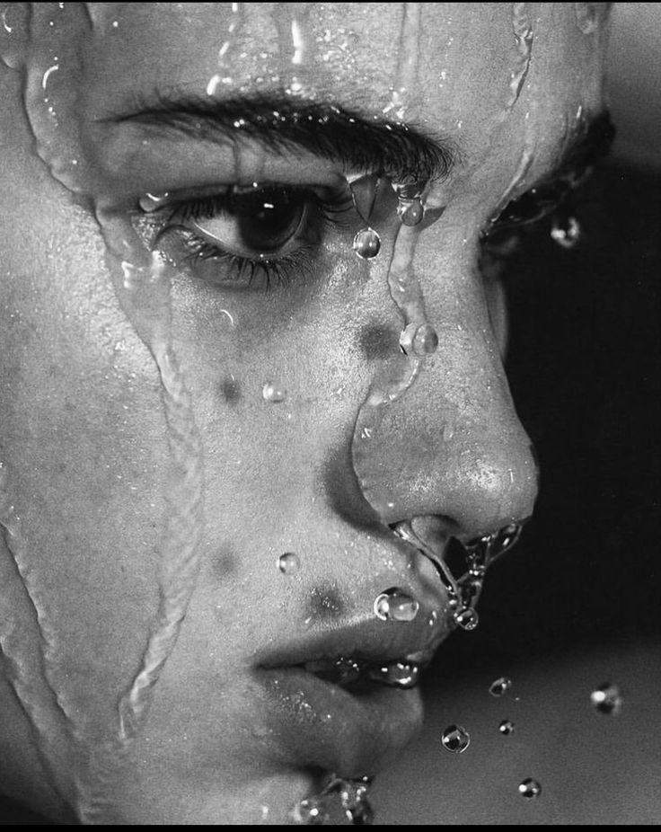 a black and white photo of a woman with water on her face