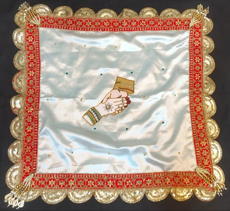 a white and red cloth with gold trimmings on the edges, featuring a hand holding