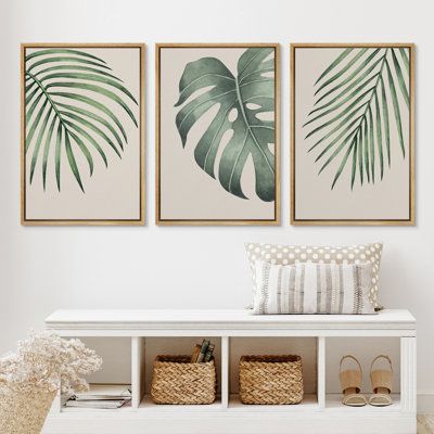 two green palm leaves are hanging on the wall above a white bench with baskets underneath it