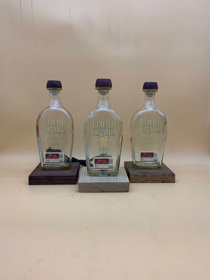 three empty glass bottles sitting on wooden bases