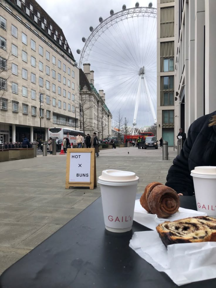 a woman sitting at a table with two cups of coffee and pastries in front of her