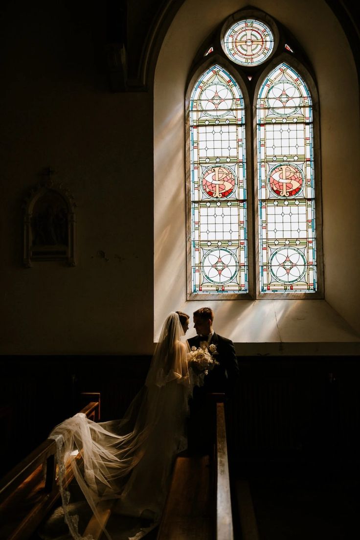 a bride and groom sitting in front of a stained glass window