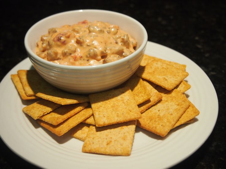 a white plate topped with crackers and a bowl of dip