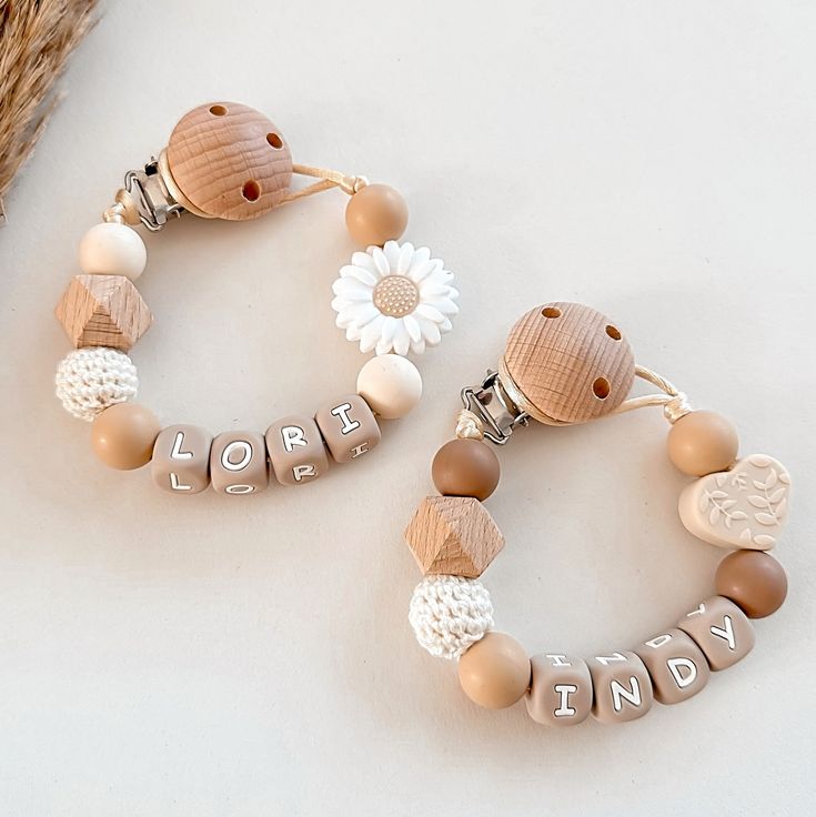 two bracelets with words and flowers on them sitting next to a basket filled with straw