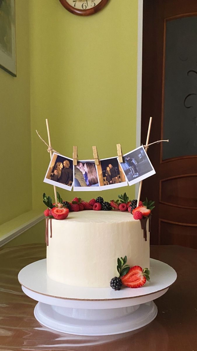 a cake with pictures on it sitting on top of a table next to a clock