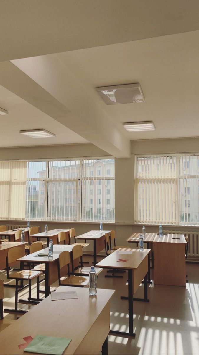 an empty classroom with desks and windows