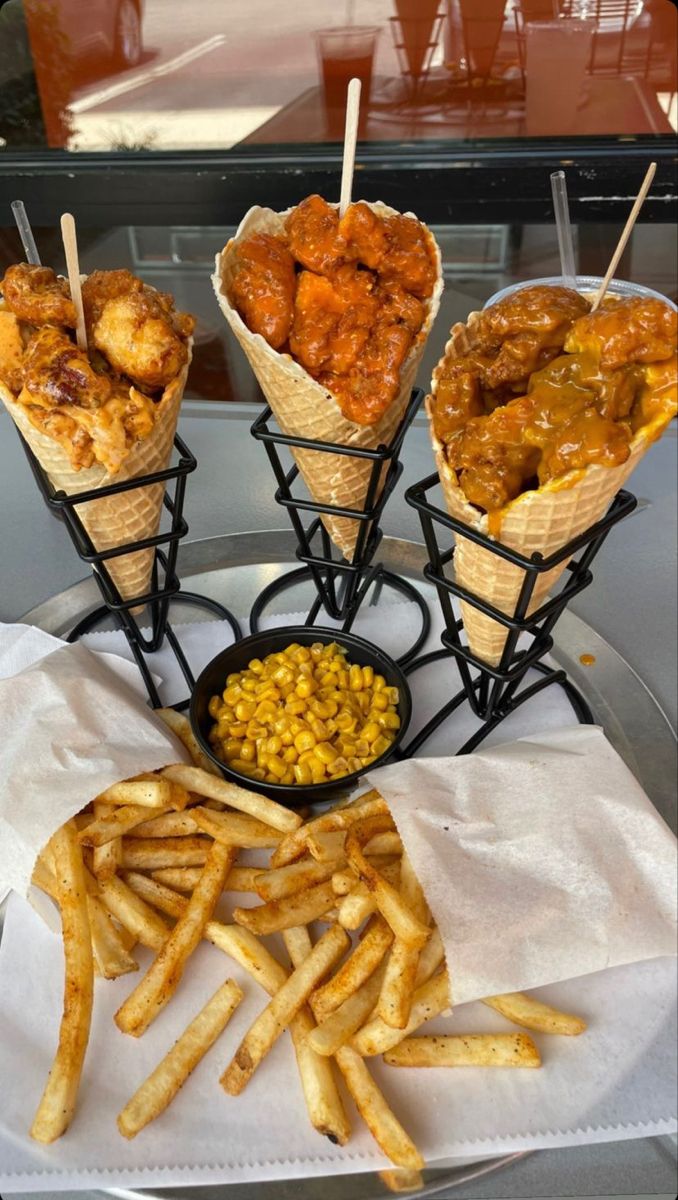 four baskets filled with food sitting on top of a white paper napkin next to fries