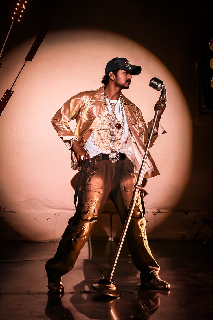 a man standing in front of a microphone with a hat on and holding a cane