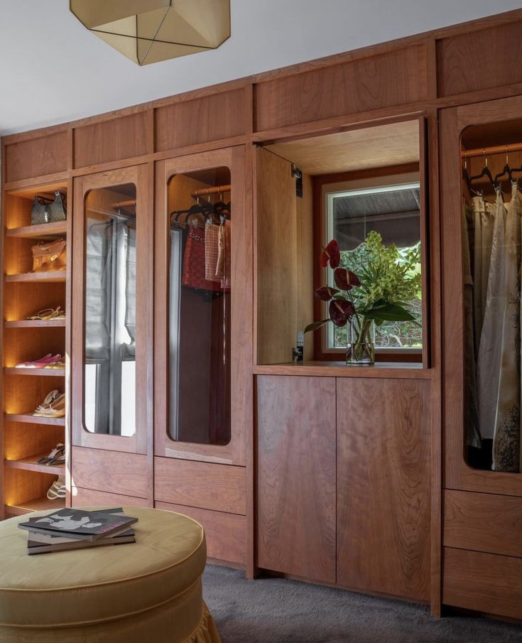 a closet with wooden doors and shelves filled with clothing, shoes and other items in it