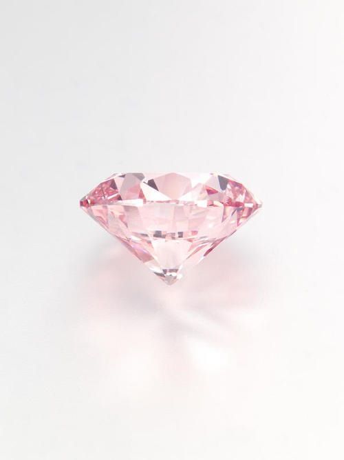 a pink diamond sitting on top of a white surface