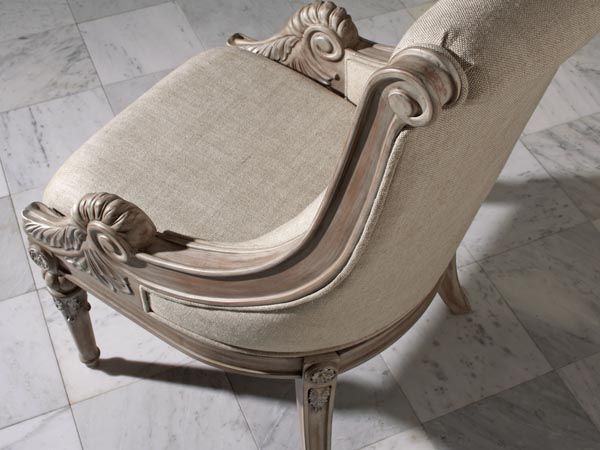 an ornately carved arm chair with beige upholstered fabric