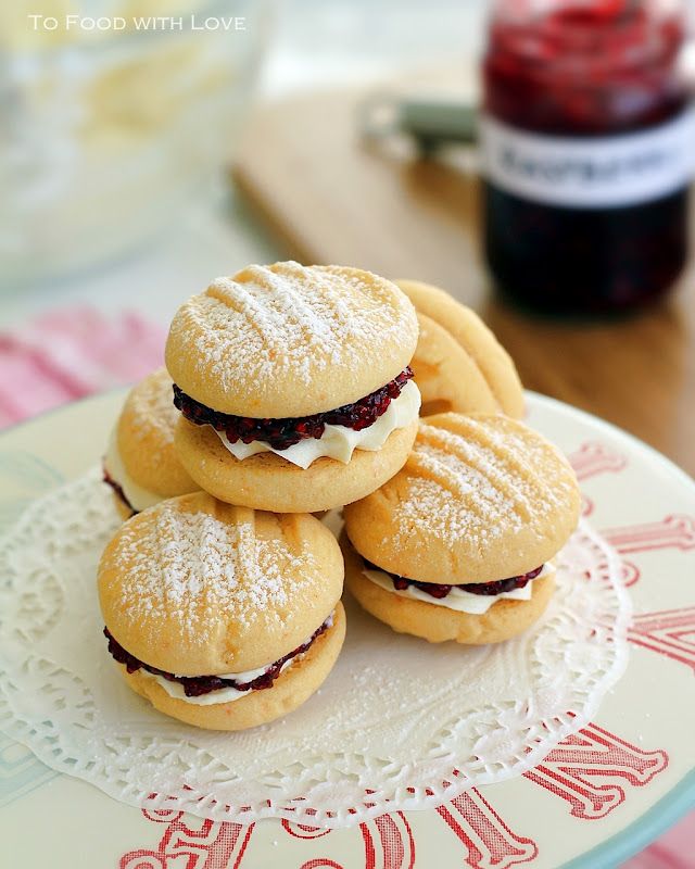 some cookies are sitting on a plate with powdered sugar and jam in the background