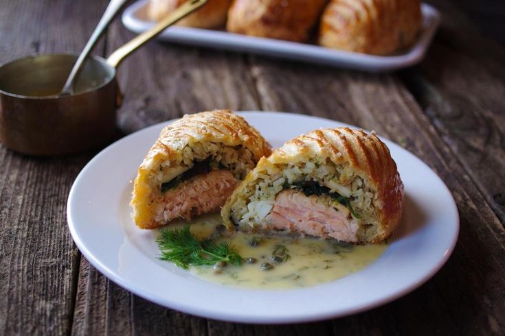 a white plate topped with meat and cheese covered in gravy next to some croissants