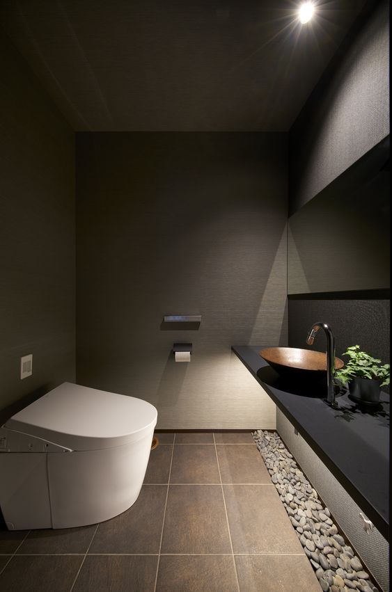 a modern bathroom with stone flooring and black walls, along with an oval shaped bathtub