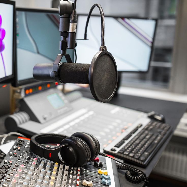 a recording studio with headphones and microphones on the desk next to two monitors