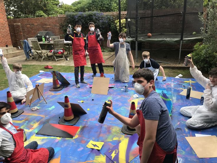 children wearing face masks doing arts and crafts in the back yard with adults around them