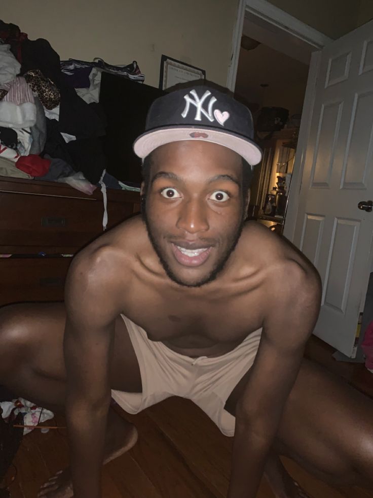 a man wearing a new york yankees hat is posing for the camera in his bedroom