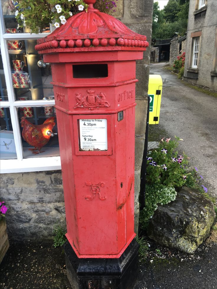 a red post box sitting in front of a building