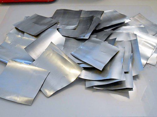 a pile of silver foil sitting on top of a white table next to a red container