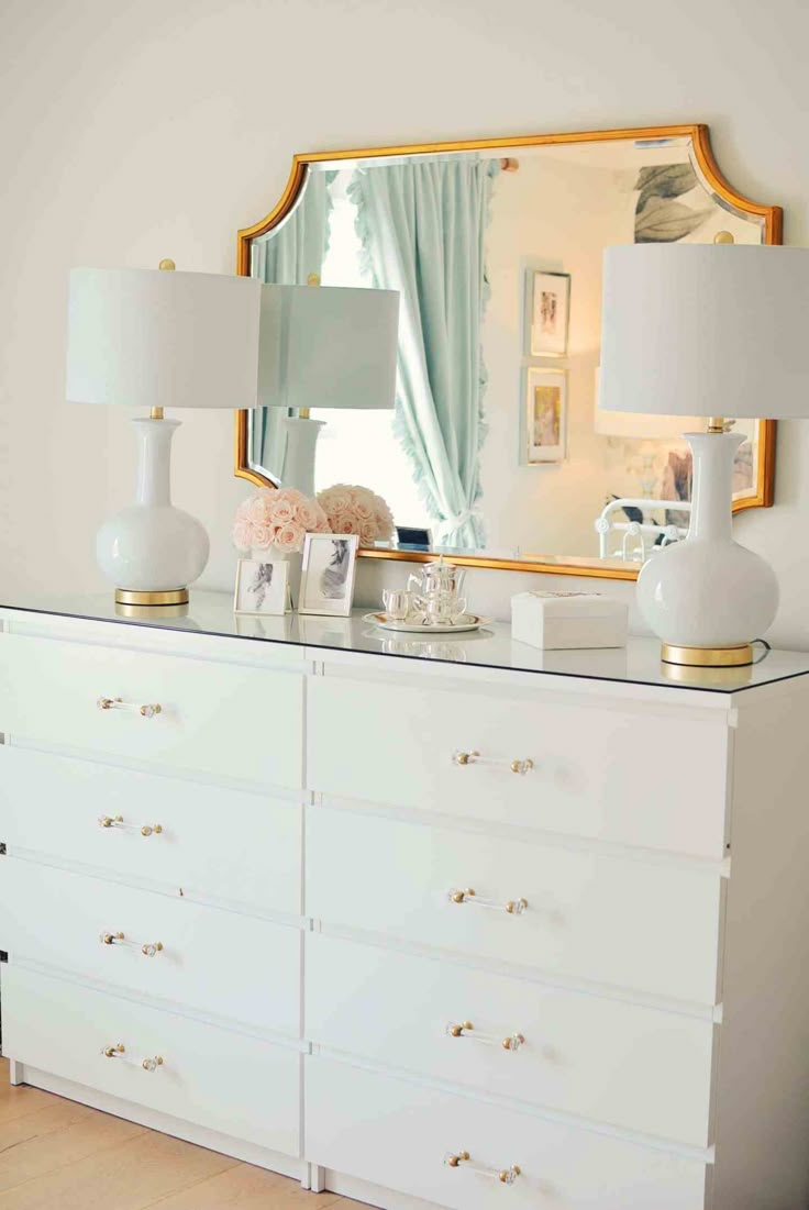 a white dresser with two lamps and a mirror