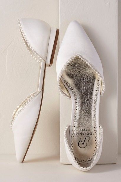 a pair of white shoes with pearls on them