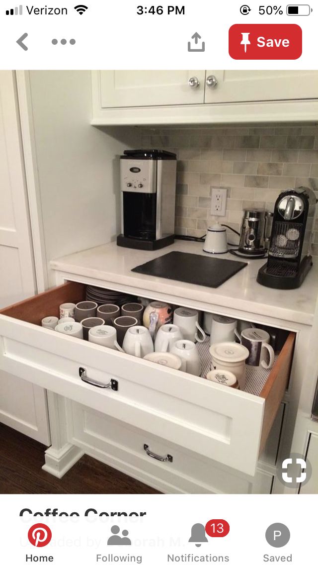 an open drawer in a kitchen filled with coffee cups and other items on the counter