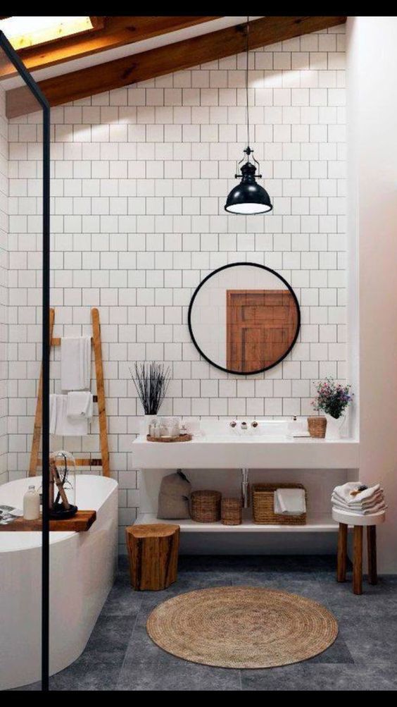 a bathroom with a round mirror above the bathtub and rug on the floor next to it