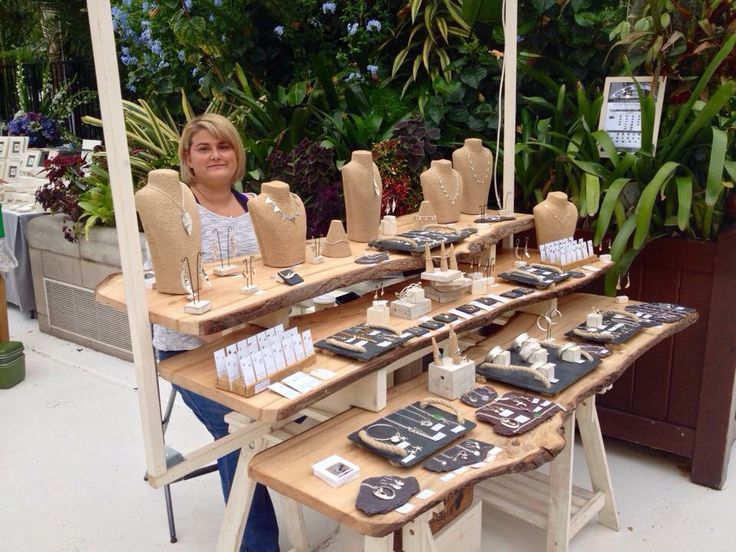 a woman standing next to a table filled with items