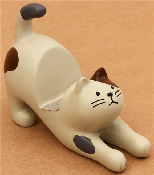 a cat figurine laying on the ground with it's tail up and eyes closed