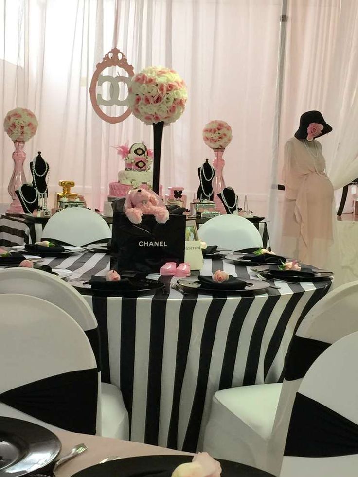 a table with black and white striped cloths, pink flowers and chandeliers