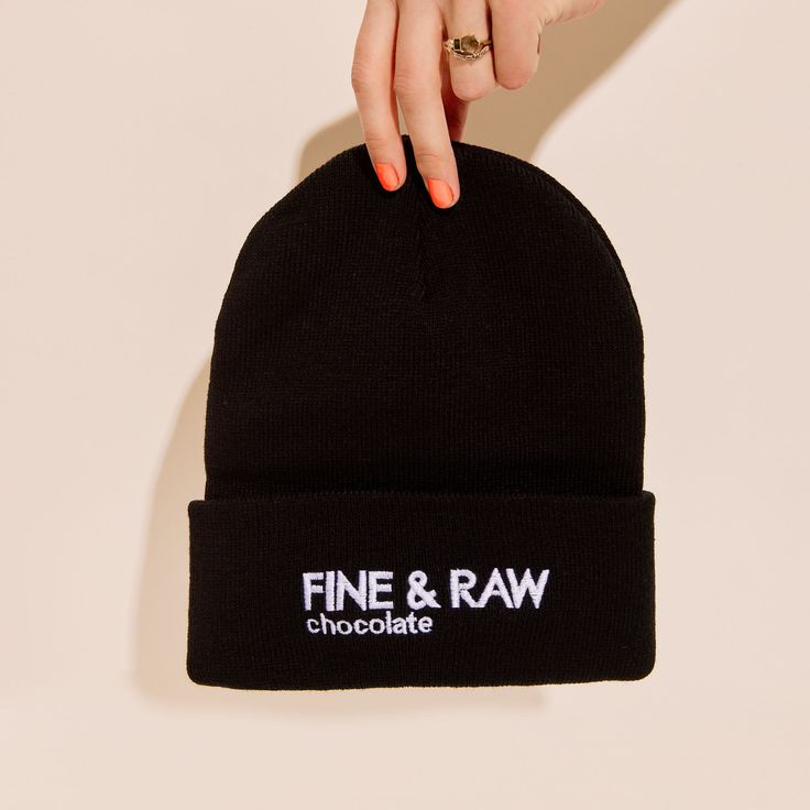 Person holding a black beanie with white FINE & RAW chocolate logo on it Black Novelty Beanie One Size Fits Most, Black Novelty Beanie For Winter, Black Warm Beanie One Size, Warm Black Cotton Beanie, Black Cotton Beanie, One Size, Neon Green, Your Head, Neon, Wonder