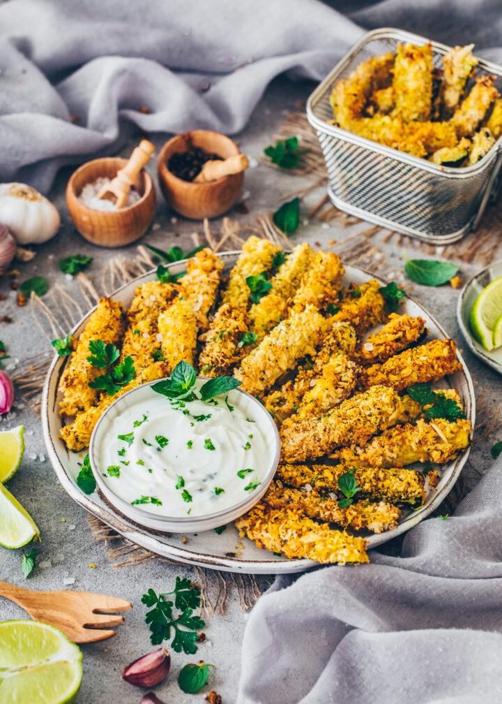 fried fish sticks on a plate with ranch dressing and lime wedges next to it