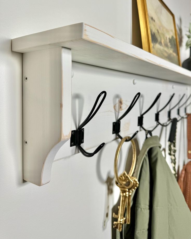 a coat rack with several coats hanging on it and two pairs of keys attached to the hooks