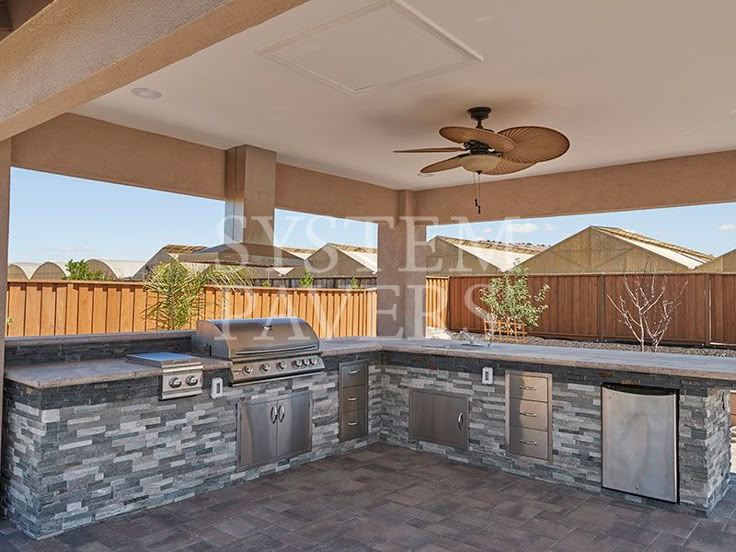 an outdoor kitchen with grill and ceiling fan