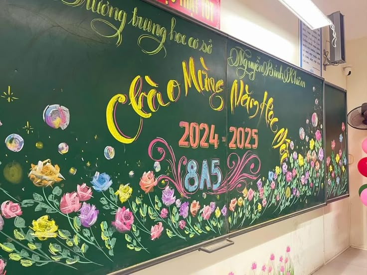 a large chalk board with flowers painted on it in a hallway next to some balloons