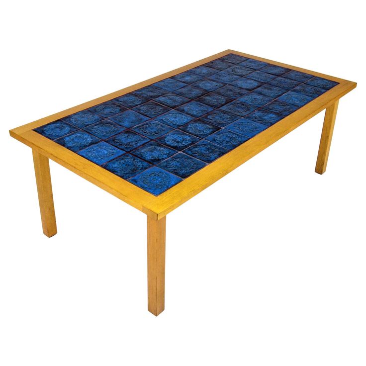 a wooden table with blue tiles on top and legs in the shape of squares, against a white background