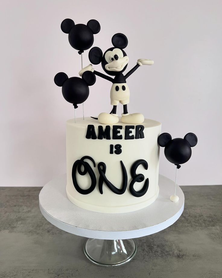 a mickey mouse birthday cake with balloons and the words amer is one on it