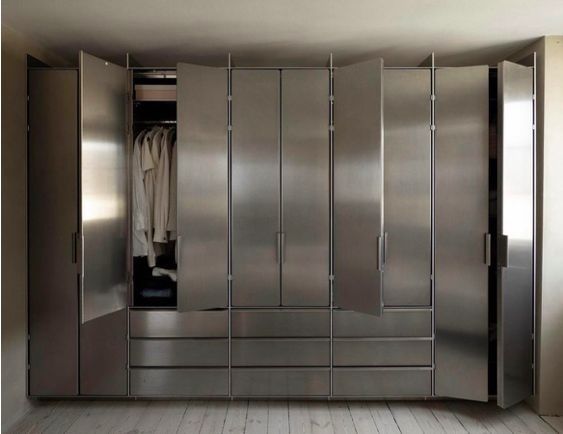 an empty walk in closet with stainless steel doors and drawers on each side, along with clothes hanging from the door