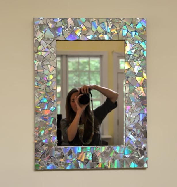 a woman taking a photo with her camera in front of a wall mirror that is made out of mosaic tiles