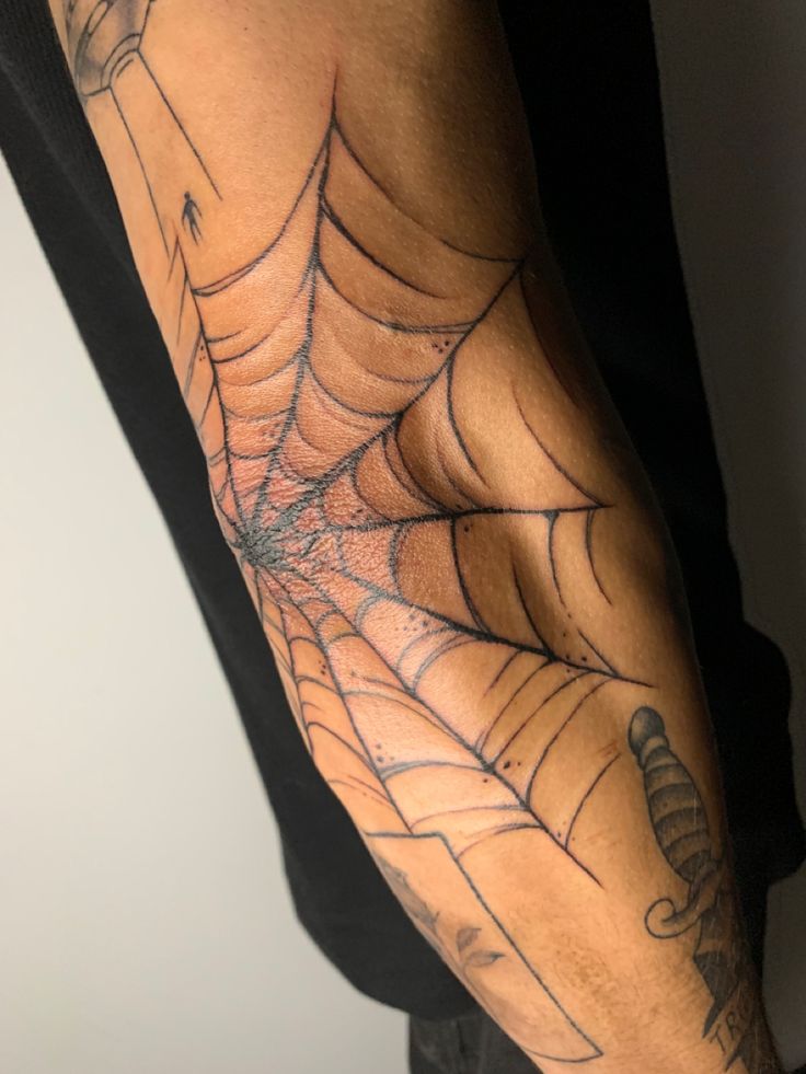 a man with a spider web tattoo on his arm