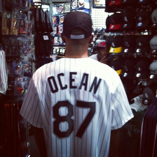 a man in a baseball uniform is looking at items on the wall behind him that are for sale