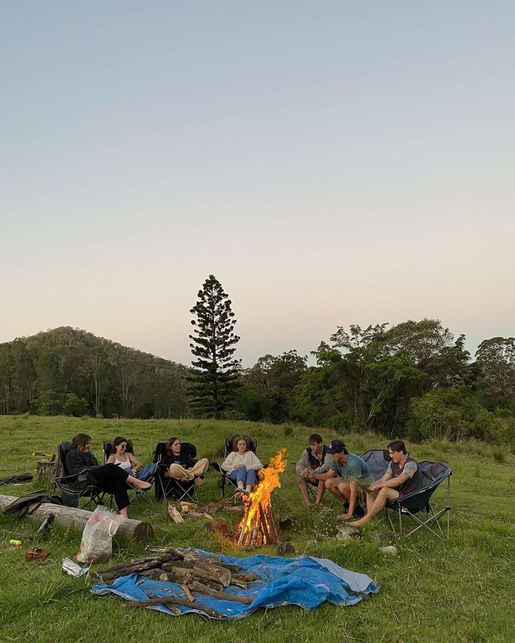 several people sitting around a campfire in the grass