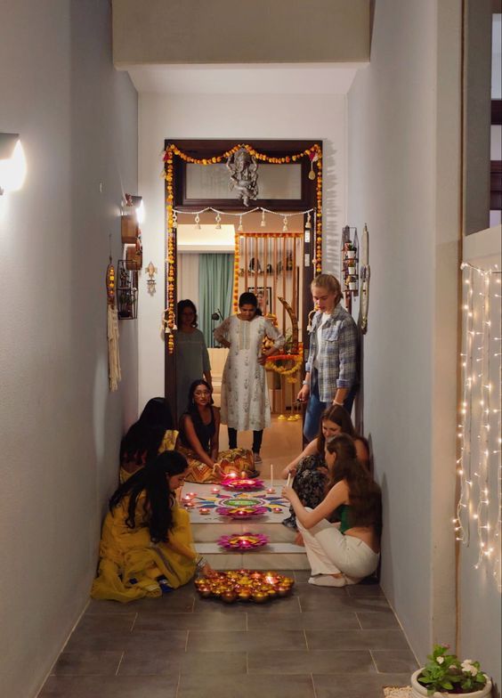 a group of people sitting around a table with food on it and lights hanging from the ceiling