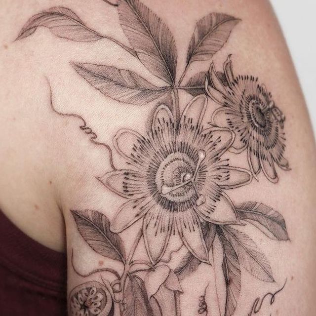 a woman's shoulder with flowers and leaves on it