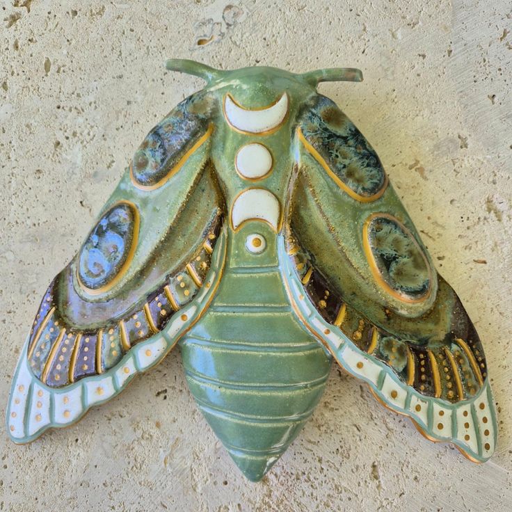 a green and white moth sitting on top of a cement floor