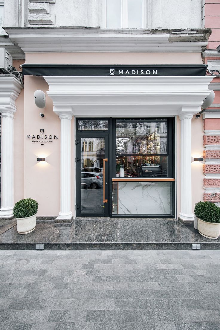 the front entrance to a store with two planters on either side and an open door