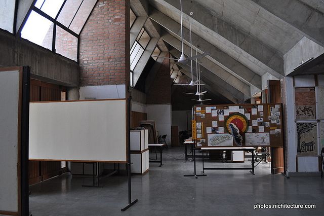 an empty room with tables, chairs and paintings hanging from the ceiling in front of them